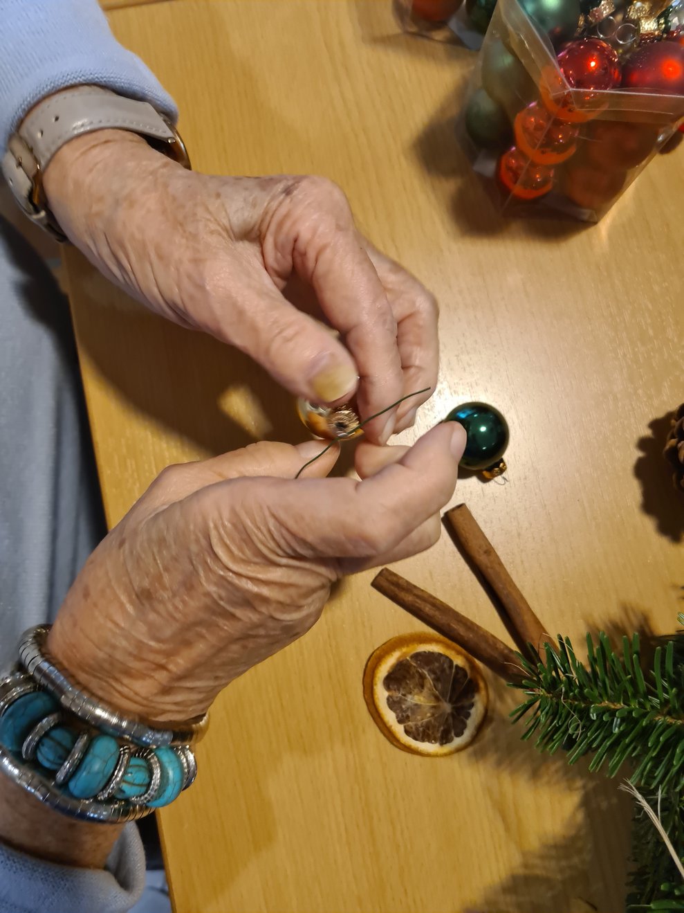 Die Dekoration wird auf den selbst gebundenen Adventkranz angebracht.