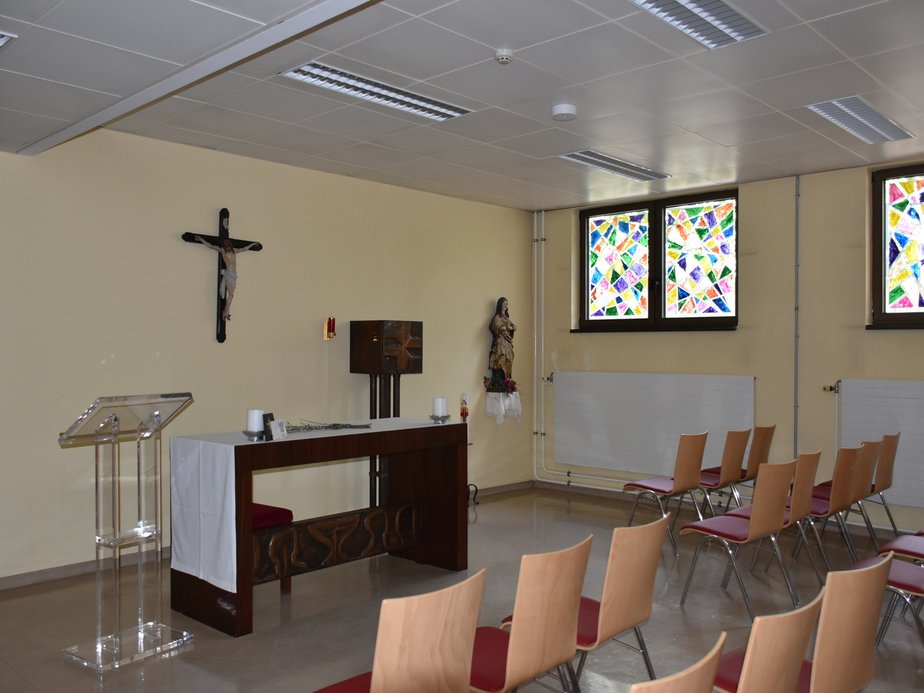 Viele Sessel stehen vor einem Altar in einer Kapelle.