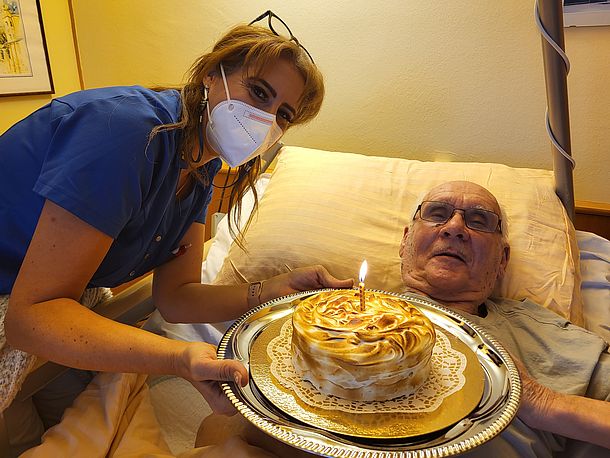 Herr W. bekommt eine Baiser-Torte von der Küche zu seinem Geburtstag überreicht durch Pflegeassistentin Manal.