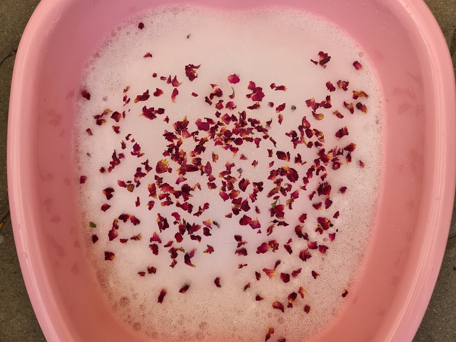 Eine kleine Wanne, die mit Blüten und Schaum gefüllt ist.
