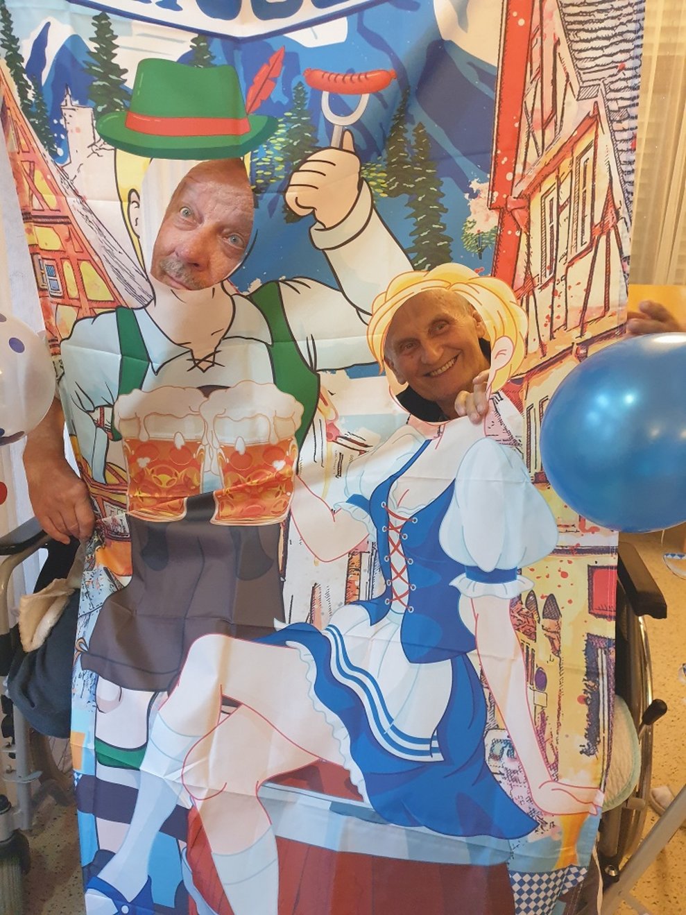 Zwei Mitarbeiter schauen durch einen Oktoberfest-Aufsteller durch.
