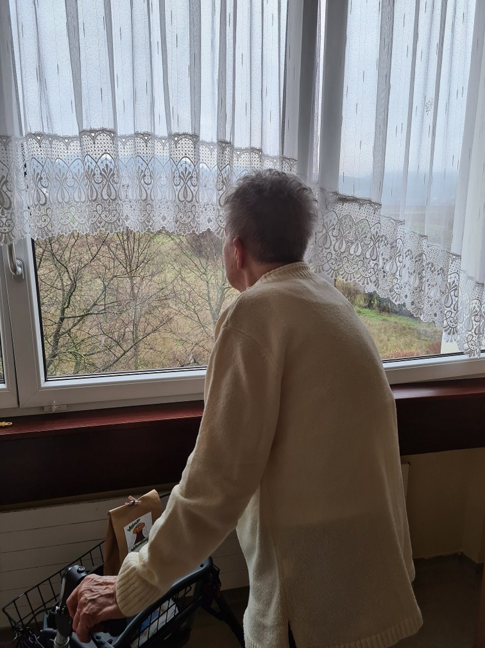 Eine Bewohnerin schaut aus dem Fenster raus.