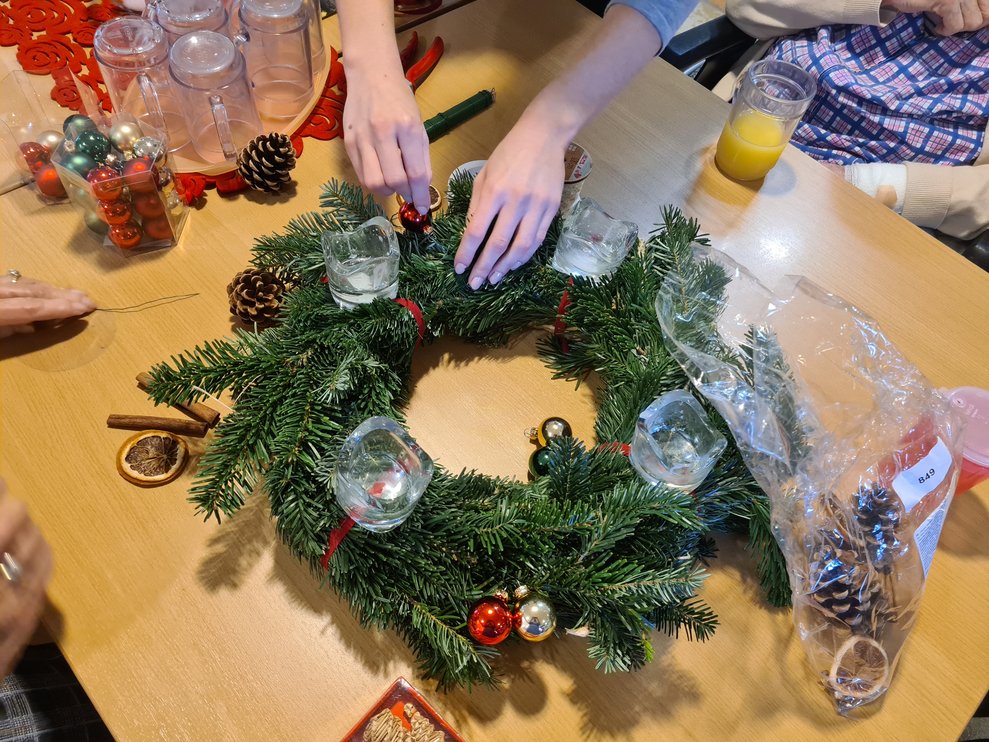 Alle helfen mit um den Adventkranz zu dekorieren.