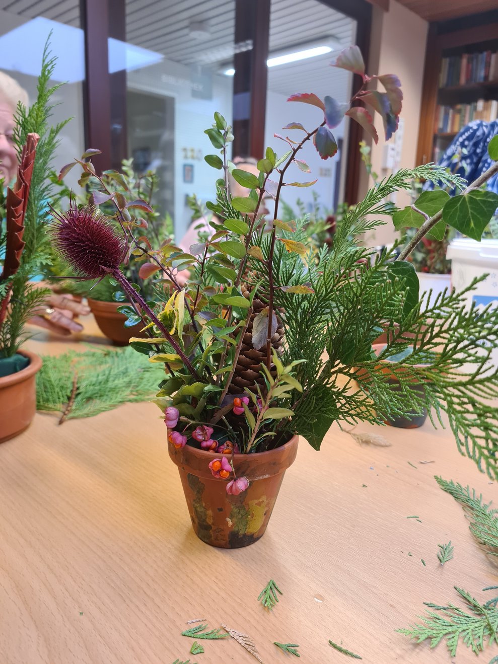 Ein Gesteck im Tontopf mit Reisig und Allerheiligendekoration.
