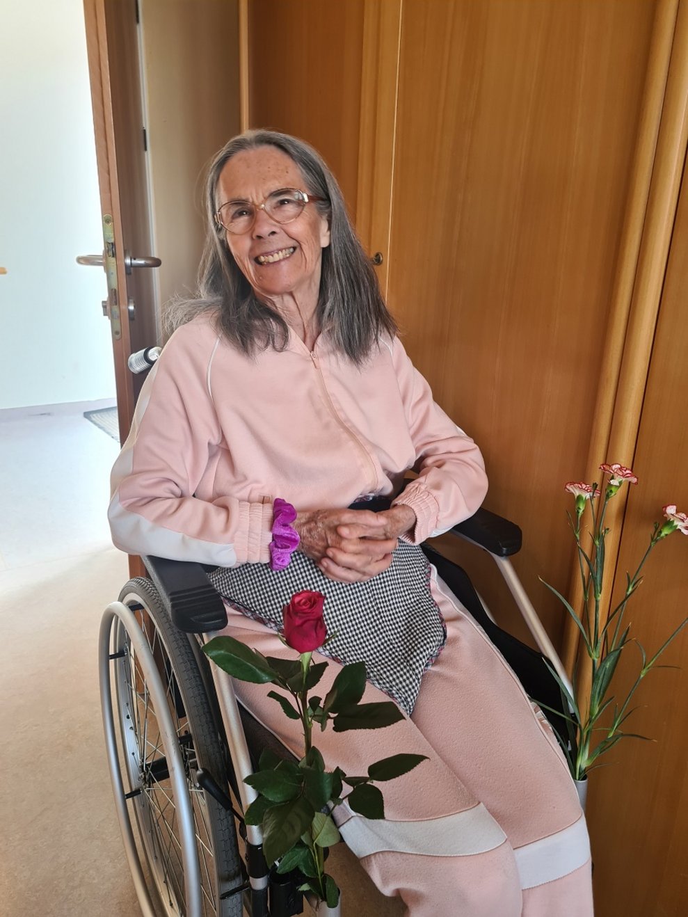 Eine Frau im Rollstuhl, an dem Blumen angebracht sind.
