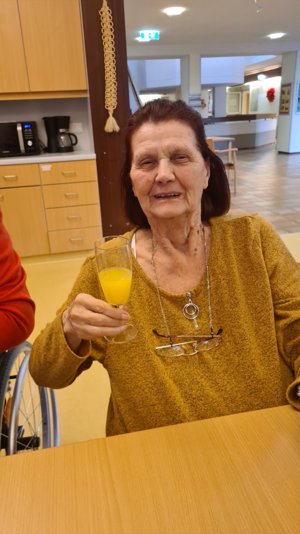 Fr. P mit einem Glas Sekt Orange in der Hand.