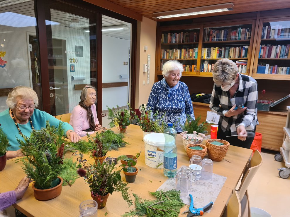 Ehrenamtliche Mitarbeiterin Doris unterstützt die Bewohnerinnen beim gestalten der Gestecke.